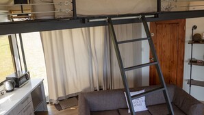 A loft-style bedroom with a bunk bed, a sofa, a ladder, a desk with a microwave, and a view of the outdoors. - Cozy Loft with big terras having a spectaculair view of San Jose (San Antonio de Escazú)