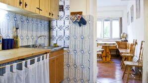 Une cuisine avec des meubles en bois, un évier et un crédence décorée. On y trouve également un coin repas avec une table et des chaises.