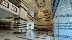 A spacious lobby with a high ceiling, chandeliers, and patterned walls. - Snood AL-Dana Hotel (Makkah)