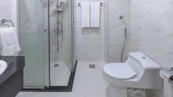 A modern bathroom with a glass-enclosed shower, a white toilet, and a marble-tiled floor.