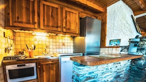 Eine Küche mit Holzausstattung, einem Edelstahl-Kühlschrank, einem Geschirrspüler und einer Stein-Kochinsel mit Schneidebrett.