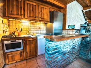 Una cucina con mobili in legno, un frigorifero in acciaio inossidabile, una lavastoviglie e un'isola in pietra con un tagliere.