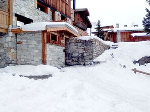 Un edificio de piedra con puerta y ventanas de madera, rodeado de nieve.