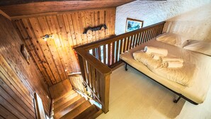 Eine Holztreppe führt zu einem Bett mit weißer Bettwäsche.