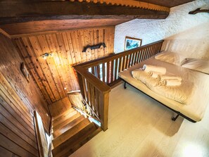 Una scala in legno conduce a un letto con lenzuola bianche.
