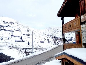 Un paisaje montañoso cubierto de nieve con un edificio que tiene balcón y paredes de piedra.