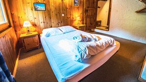 Ein Zimmer mit Holzwänden, einem Bett, zwei Nachttischen und einem an der Wand hängenden Bild.