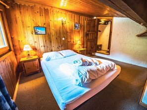 Una stanza con pannelli in legno, un letto, due comodini e un quadro appeso al muro.