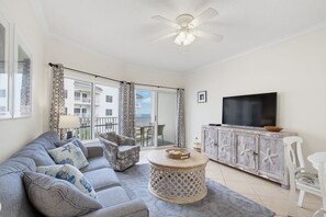 A living room with a sofa, armchair, TV, and a wooden cabinet.