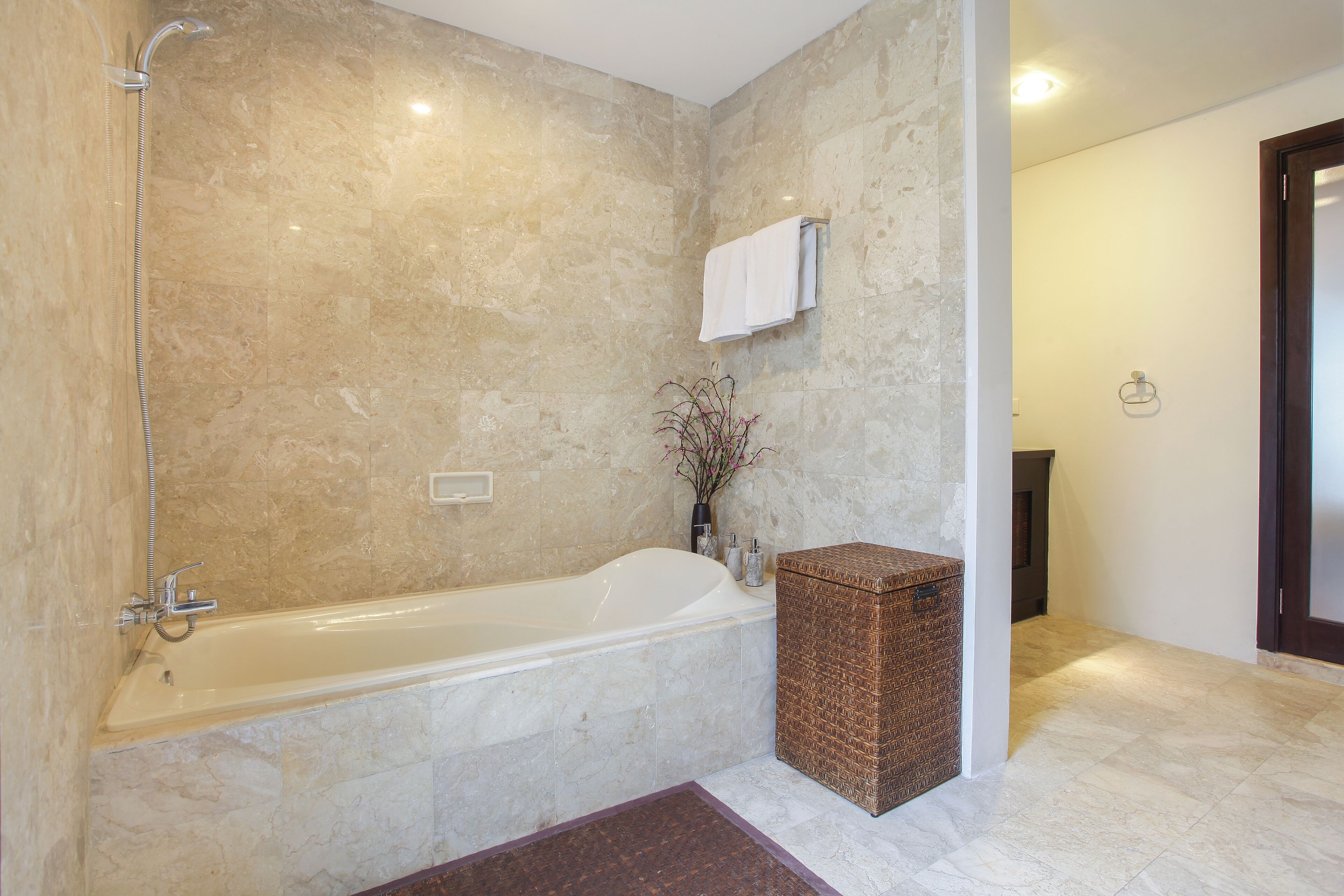Un baño con una bañera, un perchero para toallas y una cesta de mimbre.