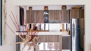 A modern kitchen with wooden cabinets, a stainless steel refrigerator, and decorative vases on the countertop. - Sunset Villa by Premier Hospitality Asia (Nusa Dua)