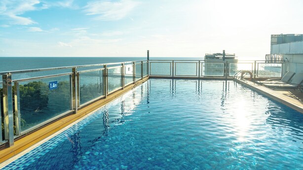 Piscina com barreira de vidro e vista para o mar.