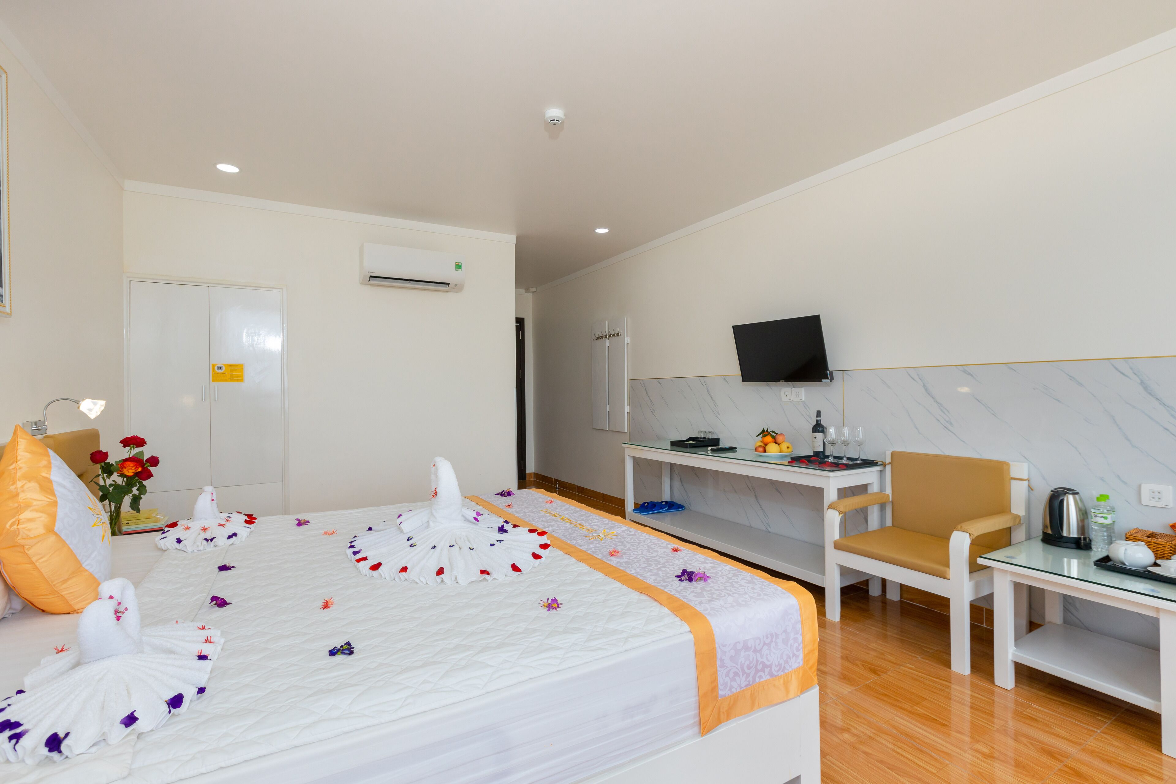 Una habitación de hotel con cama, escritorio, silla, televisor y minibar.