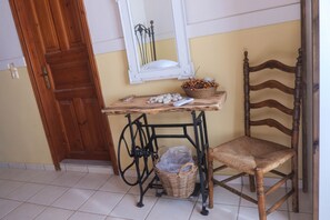 Cozy retreat with a traditional door, a small table, and a wicker chair, featuring a mirror and a convenient storage basket.