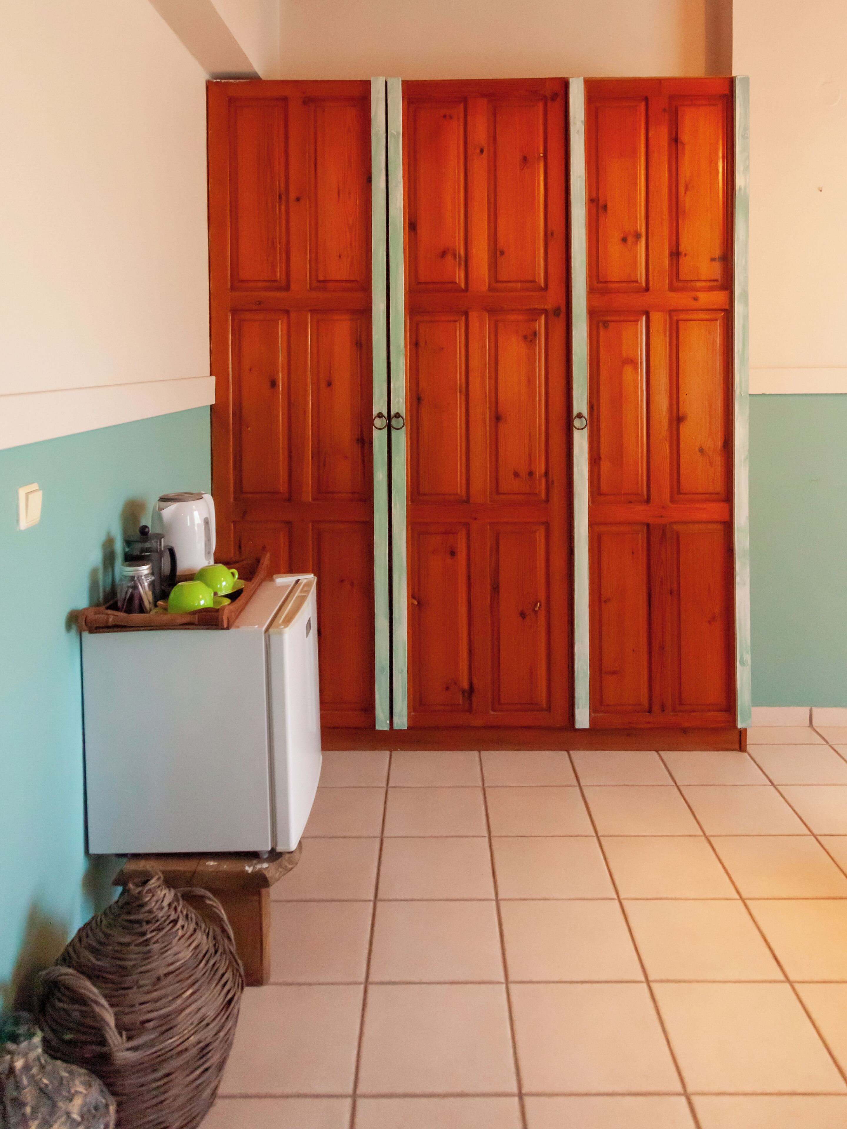 Eine Küche mit Kühlschrank, Kaffeemaschine und einem Korbwäscheschrank.