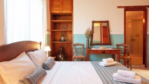 A neatly arranged hotel room with a bed, a desk, a chair, and a mirror. - Amnisiades Apartments (Heraklion)