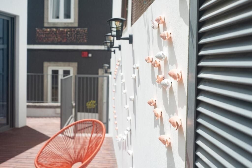 Ein Gebäude mit einer weißen Wand, einem roten Stuhl und einer Reihe kleiner, pinkfarbener Objekte an der Wand.