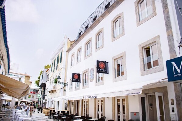 En gata med flera byggnader, bland annat en restaurang som heter ”KAVIA” och ett café som heter ”CHAC NOOL”.