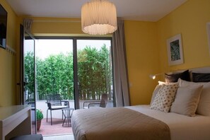 Ett hotellrum med en säng, ett skrivbord, en stol och utsikt över grönområden genom fönstret.