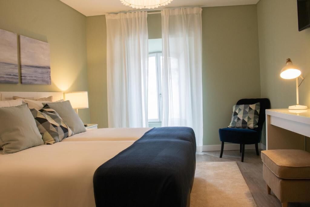 Una habitación de hotel con cama, escritorio, silla y lámpara.