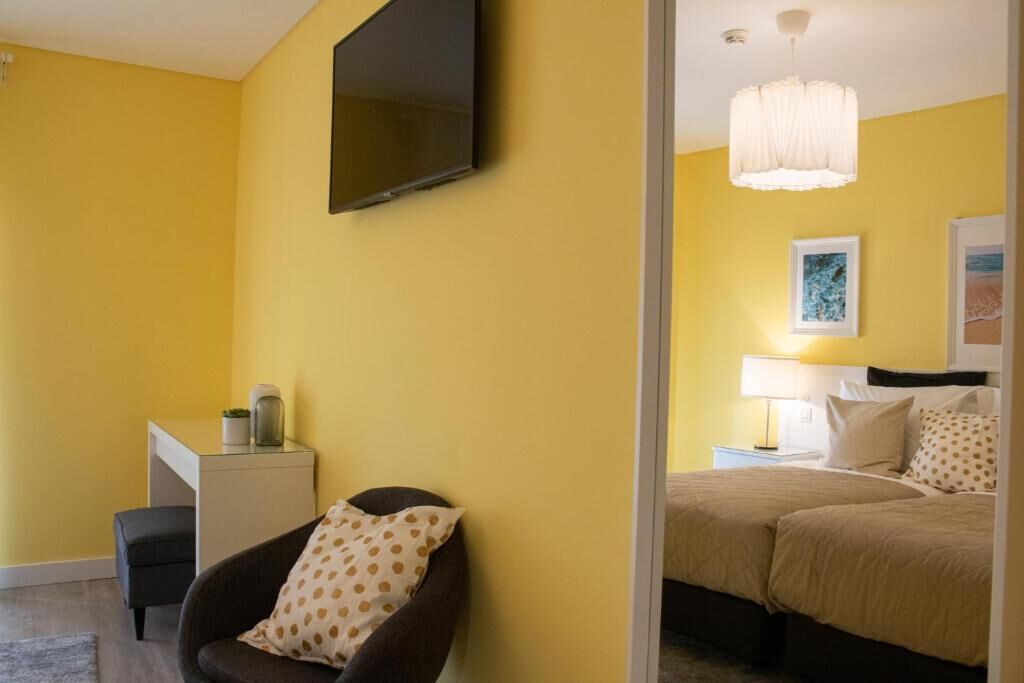 Een hotelkamer met een bed, een bureau, een stoel, een aan de muur bevestigde televisie en een bedlamp.