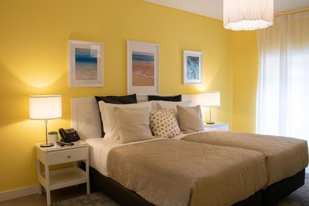 A hotel room with a bed, two bedside tables, a lamp, and three framed pictures on the wall.