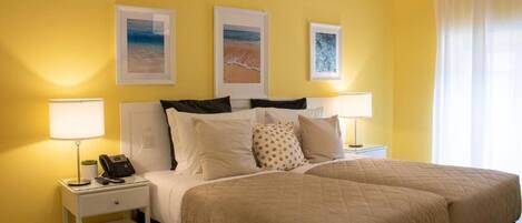 A hotel room with a bed, two bedside tables, a lamp, and three framed pictures on the wall.