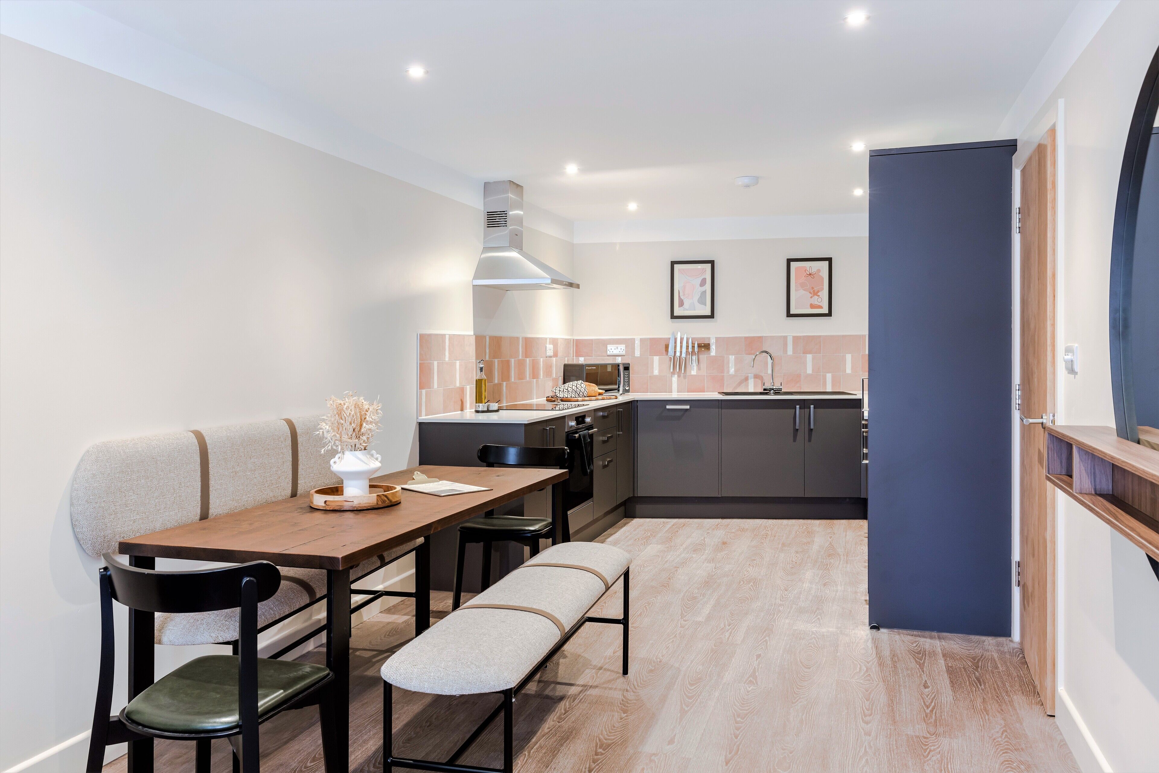A compact kitchen with modern appliances, a dining area with a bench, and a small seating area.