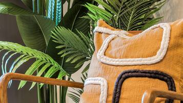 Un sillón de cuero con un cojín de estampado geométrico, junto a una cesta de mimbre con plantas verdes.
