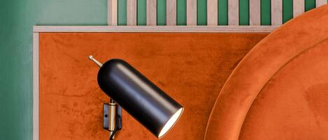 A room with a green wall, an orange sofa, and a black lamp on a wooden panel.