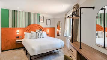 Un dormitorio moderno con cama, mesitas de noche, cómoda, espejo y ventana con cortinas.