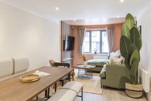 Una sala de estar moderna con una mesa de comedor de madera, un sofá verde y una planta grande.