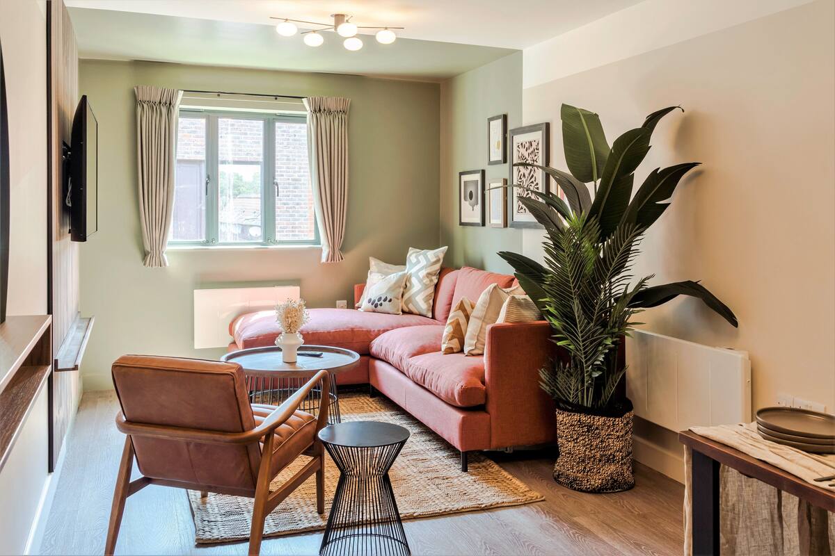 A cozy living room with a sectional sofa, a coffee table, and a large potted plant.