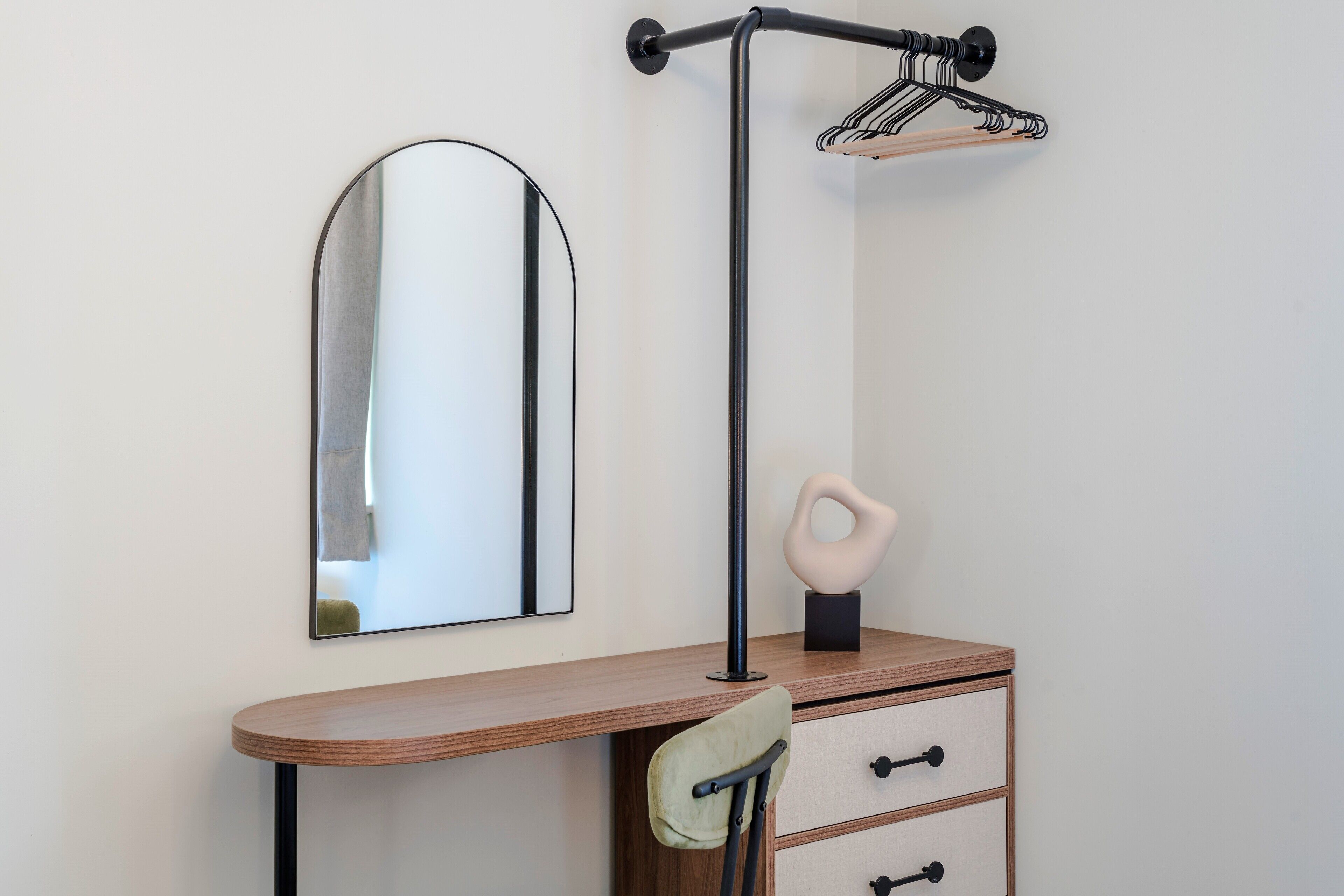Ein Schreibtisch in der Ecke mit Spiegel, Lampe und einem kleinen Schrank.