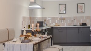 Een moderne keuken met grijze kastjes, een roestvrijstalen afzuigkap en een eethoek met een tafel voor vier personen.