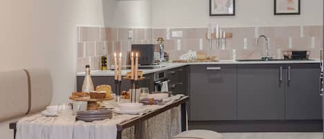 A modern kitchen with grey cabinets, a stainless steel range hood, and a dining area with a table set for four.