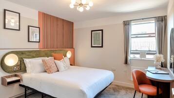 A hotel room with a bed, a desk, and a view of the city.