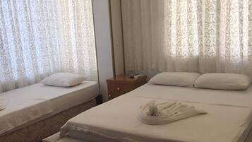 A hotel room with two beds, a wooden nightstand, and a ceiling light.