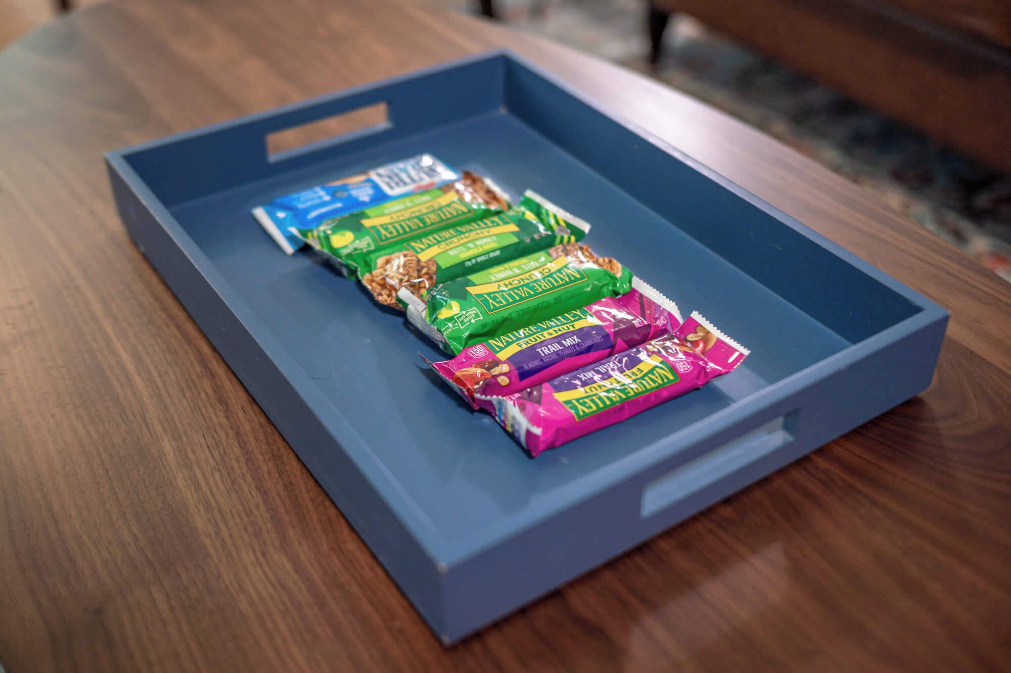 A blue tray with various snack packages on a wooden table.