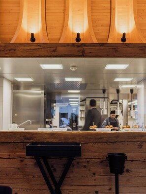 L’intérieur d’un restaurant avec des lambris en bois, un comptoir et une personne qui prépare des plats.