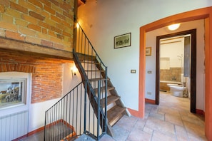 A staircase with a brick wall and a framed picture, leading to a bathroom with a toilet and sink. - Timeless l' Antico Mulino Della Bozza (Brebbia)