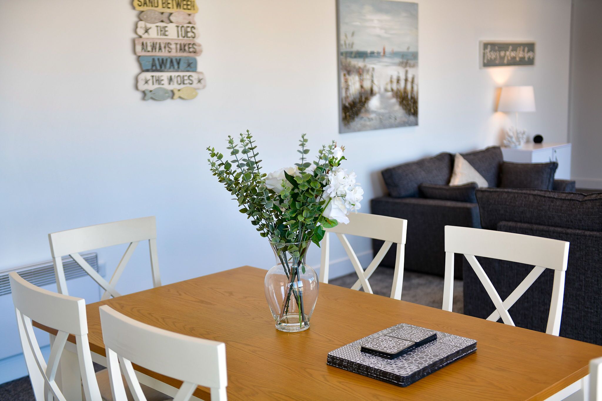 A dining table with a vase of flowers, white chairs, and a notebook.