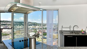 A modern kitchen with a glass enclosure, a built-in stove, and a view of the city. - Just Stay Wales - Meridian Tower (Swansea)