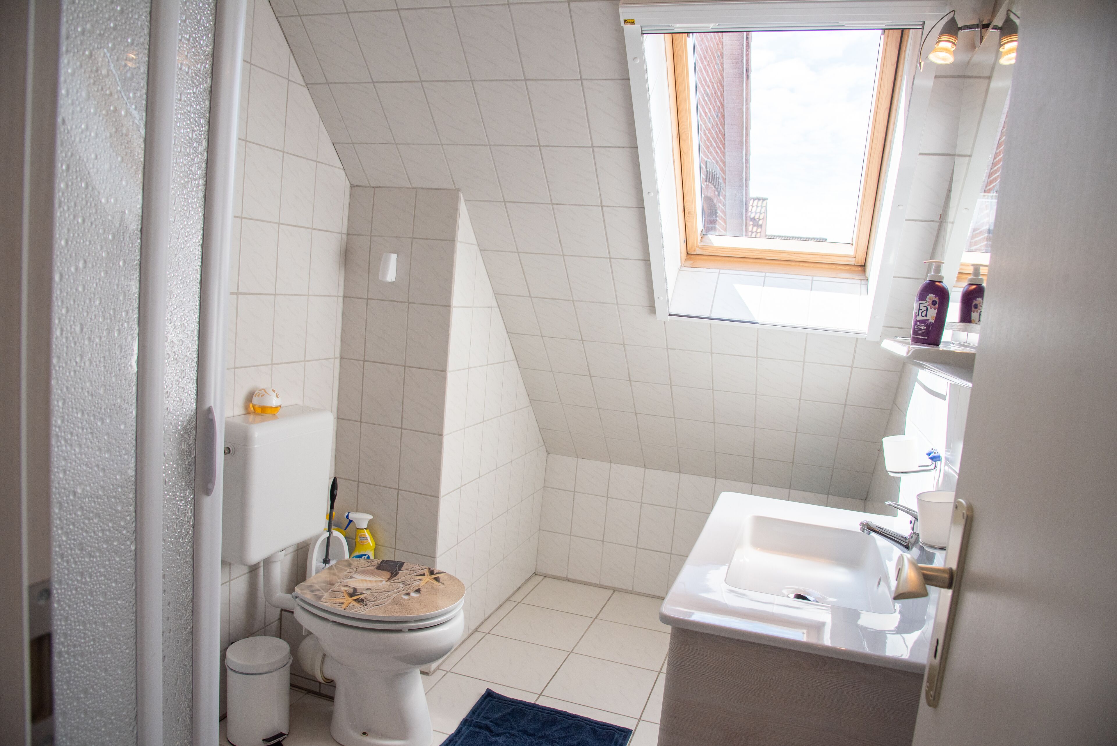 Ein kleines Badezimmer mit Toilette, Waschbecken und Fenster.