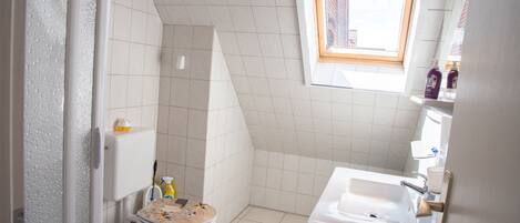 Ein kleines Badezimmer mit Toilette, Waschbecken und Fenster.