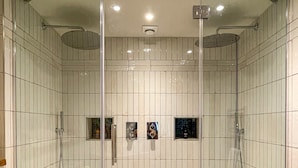 A walk-in shower with a glass door, tiled walls, and a patterned floor. - Parador44 (Cardiff)