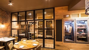 A restaurant with a brick wall, wooden tables, and a wine rack. - Parador44 (Cardiff)