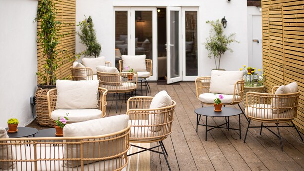 A patio area with wicker furniture and potted plants. - Parador44 (Cardiff)