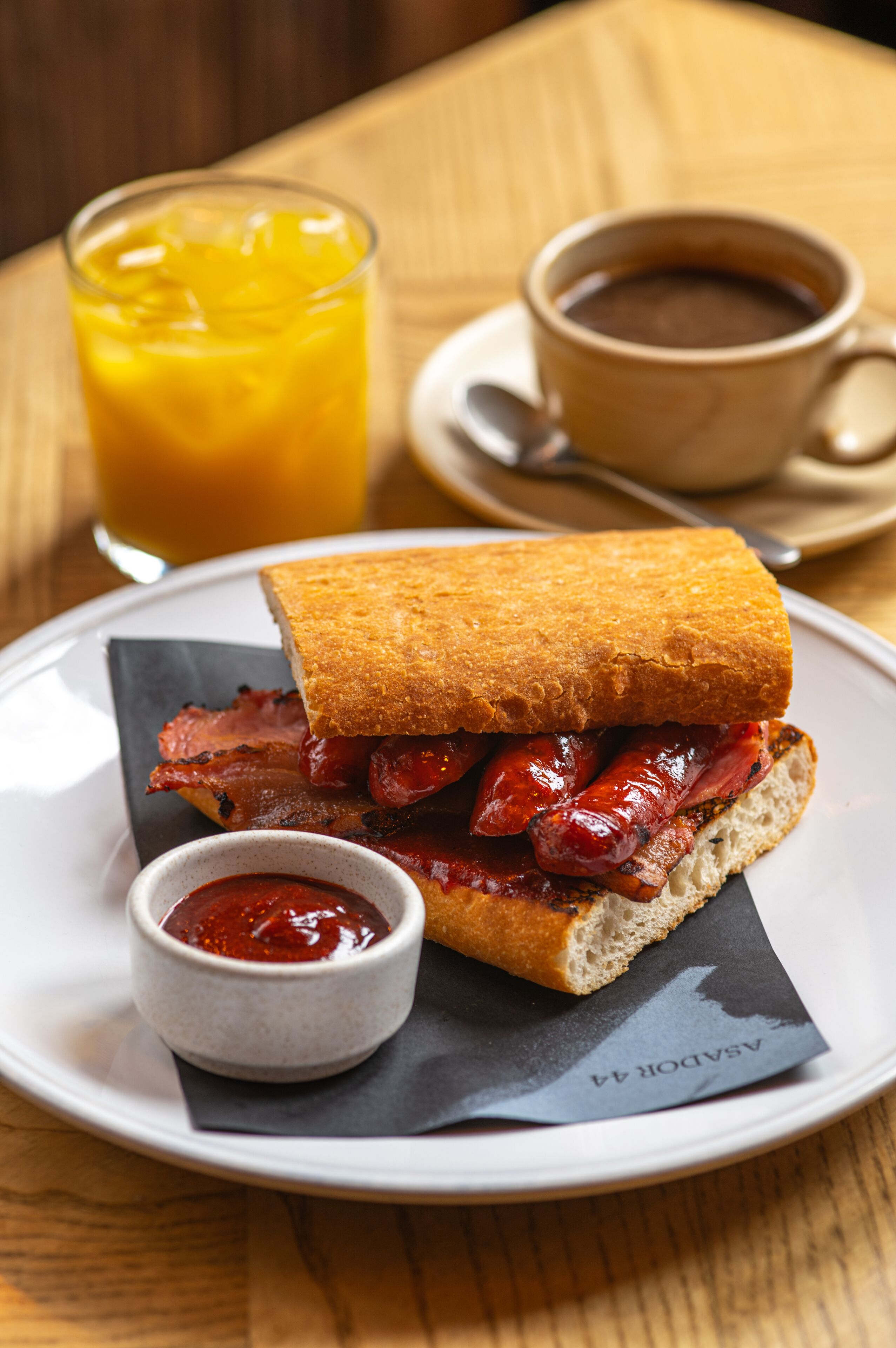 Un sandwich sur une assiette, accompagné d’une tasse de café et d’un verre de jus d’orange.