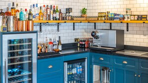 A kitchen with blue cabinets, a coffee machine, and various bottles and jars on shelves. - Parador44 (Cardiff)